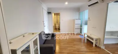 Modern living room with wooden flooring and air conditioning, leading to a compact bathroom.