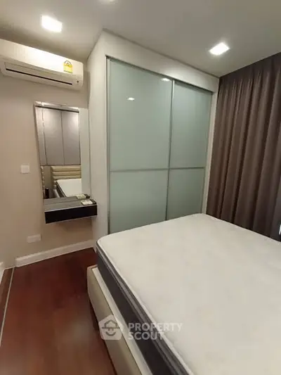 Modern bedroom with sleek design, featuring a large bed, built-in wardrobe, and air conditioning.