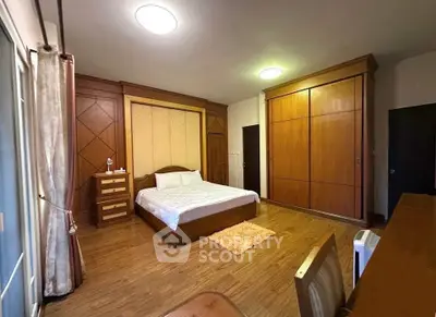 Spacious bedroom with wooden flooring and large wardrobe in a modern home.