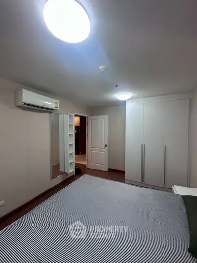 Spacious bedroom with modern air conditioning and ample closet space in a stylish apartment.