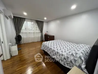 Spacious bedroom with wooden flooring and modern decor in a bright apartment.