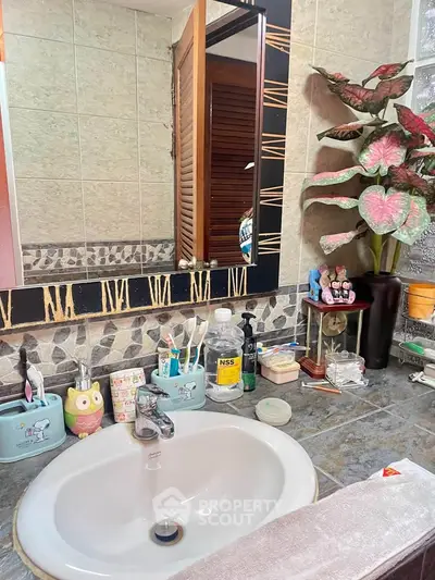 Charming bathroom with decorative tiles and modern sink, featuring stylish decor and ample counter space.