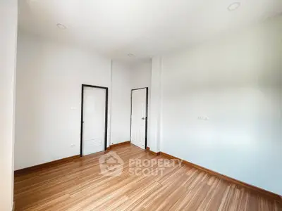 Spacious empty room with wooden flooring and white walls, perfect for customization.