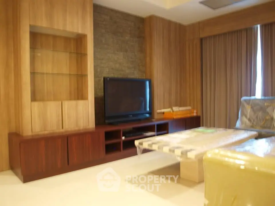 Modern living room with sleek wooden furniture and large TV, perfect for relaxation and entertainment.