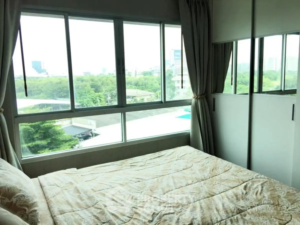 Bright bedroom with large windows offering a scenic view of greenery and cityscape.