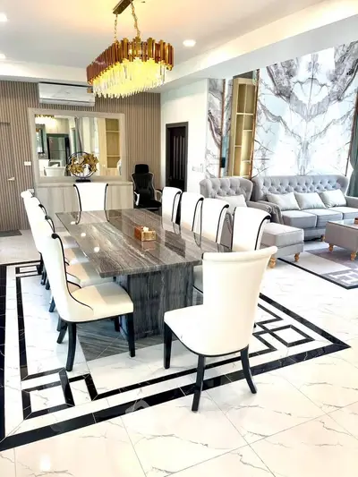 Luxurious open-plan living and dining area with elegant chandelier and marble flooring.