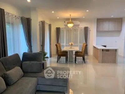 Elegant open-plan living and dining area with modern furnishings and chandelier.