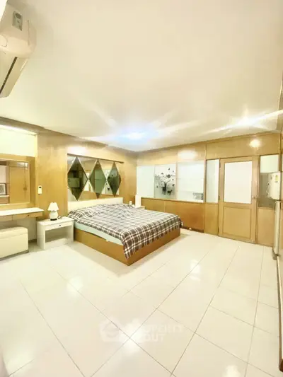 Spacious bedroom with modern decor and ample natural light, featuring a cozy bed and stylish furnishings.