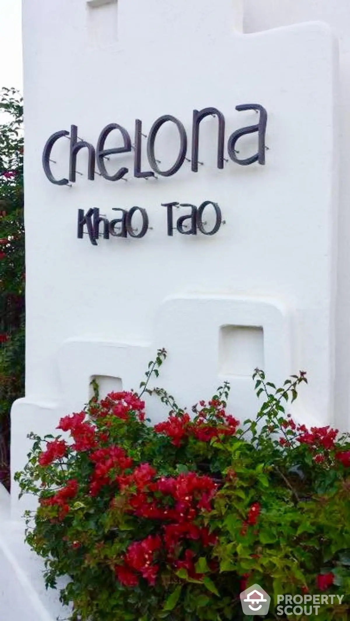 Chelona Khao Tao entrance sign with vibrant red flowers