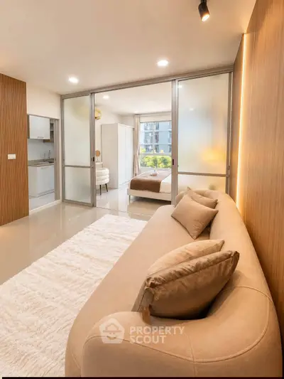 Modern apartment interior with cozy living room and elegant bedroom, featuring sliding glass doors and stylish decor.