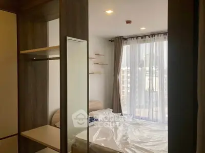 Modern bedroom with large window and city view, featuring sleek wooden furniture and neutral decor.