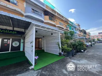 Charming townhouse exterior with lush greenery and covered entrance in vibrant neighborhood.