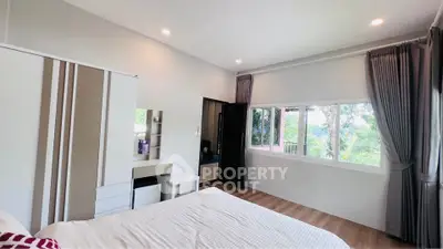Spacious bedroom with scenic window view and modern furnishings
