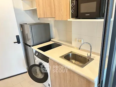 Modern compact kitchen with washing machine, fridge, and microwave in sleek design.