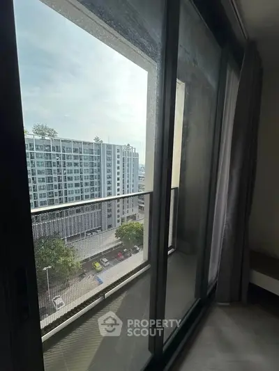 Modern apartment balcony with city view and large sliding glass doors.
