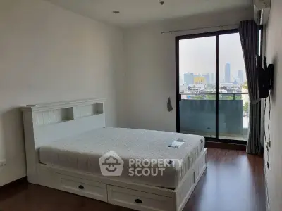 Spacious bedroom with city view and balcony access in modern apartment.