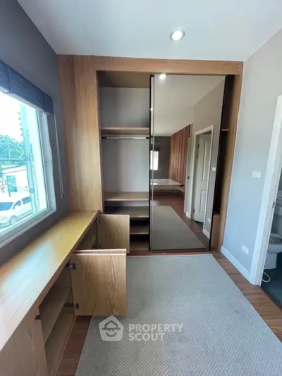 Spacious bedroom with built-in wooden wardrobe and large window