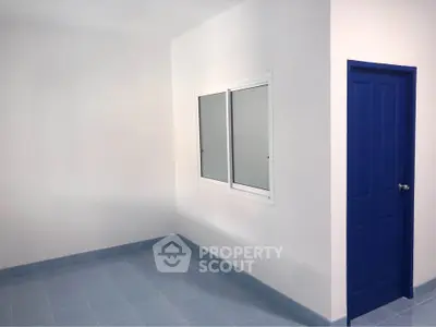 Minimalist room with blue door and tiled floor, perfect for creative design opportunities.
