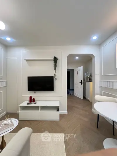 Elegant living room with modern decor and wall-mounted TV, featuring stylish furniture and soft lighting.