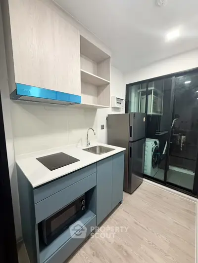 Modern kitchen with sleek appliances and open layout, featuring a glass door leading to a utility area.