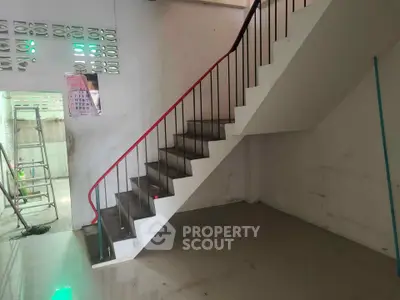 Spacious interior with modern staircase and tiled flooring, ideal for renovation or customization.
