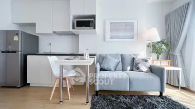 Modern living room with sleek kitchen, cozy sofa, and stylish decor in bright, airy apartment.