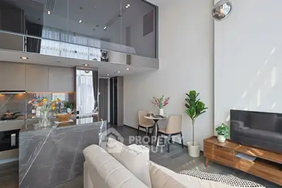 Modern open-plan living room with stylish kitchen and dining area, featuring high ceilings and elegant decor.
