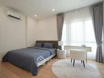 Modern bedroom with elegant decor, featuring a cozy bed, stylish chair, and natural light from large windows.