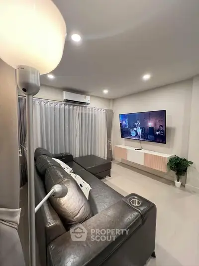 Modern living room with sleek leather sofa and wall-mounted TV, perfect for entertainment.