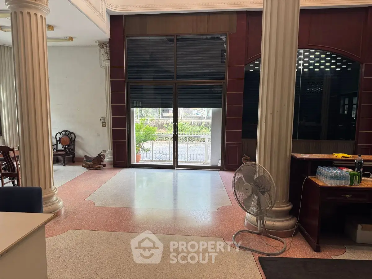Spacious interior with elegant columns and large windows in a luxurious property.