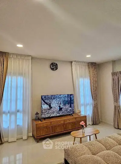 Spacious living room with modern decor and large TV, perfect for relaxation.