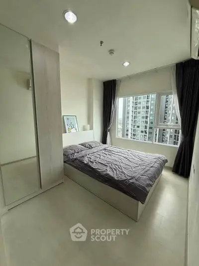 Modern bedroom with large window and city view in high-rise apartment
