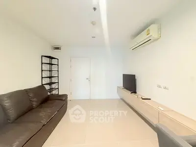 Modern living room with sleek furniture and wall-mounted TV in a minimalist apartment.