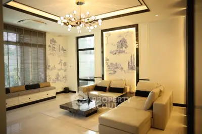 Luxurious living room with elegant decor and modern chandelier, featuring a spacious seating area and large windows.