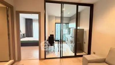 Modern apartment interior with glass partition, cozy living area, and sleek kitchen design.