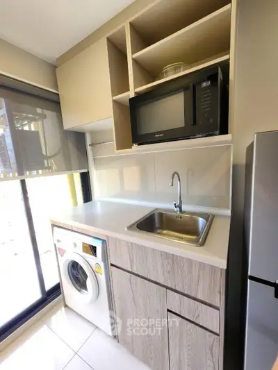 Modern kitchen with built-in microwave, washing machine, and sleek cabinetry.