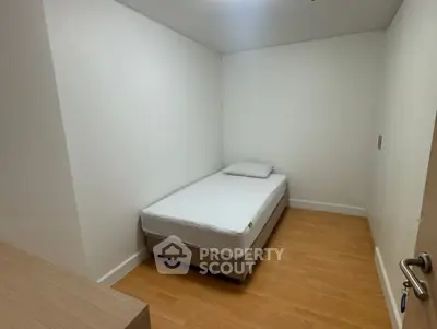 Minimalist bedroom with single bed and wooden flooring, perfect for cozy living.