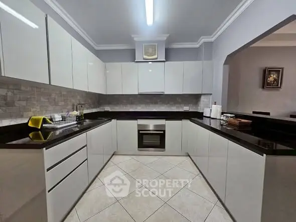 Modern kitchen with sleek cabinetry and built-in oven in a spacious layout.