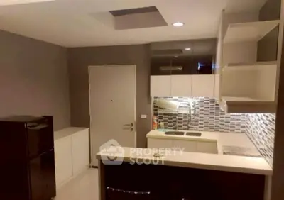Modern kitchen with sleek cabinetry and stylish backsplash in compact apartment.
