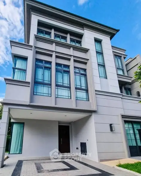 Modern multi-story residential building with large windows and driveway