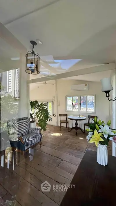 Charming sunlit room with vintage decor and wooden flooring, perfect for cozy gatherings.