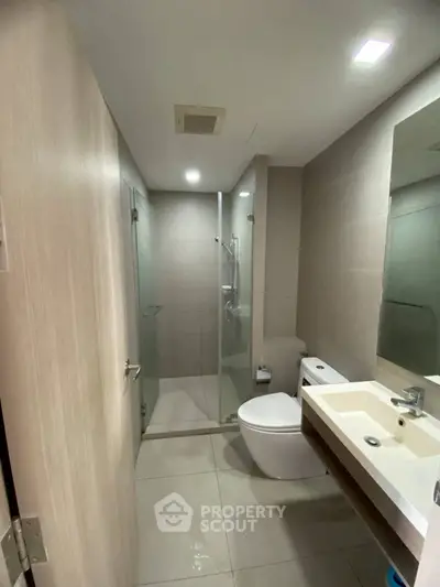Modern bathroom with glass shower and sleek fixtures in contemporary apartment.