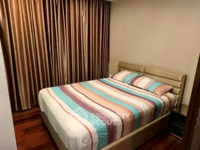 Cozy bedroom with striped bedding and elegant curtains in a modern apartment.