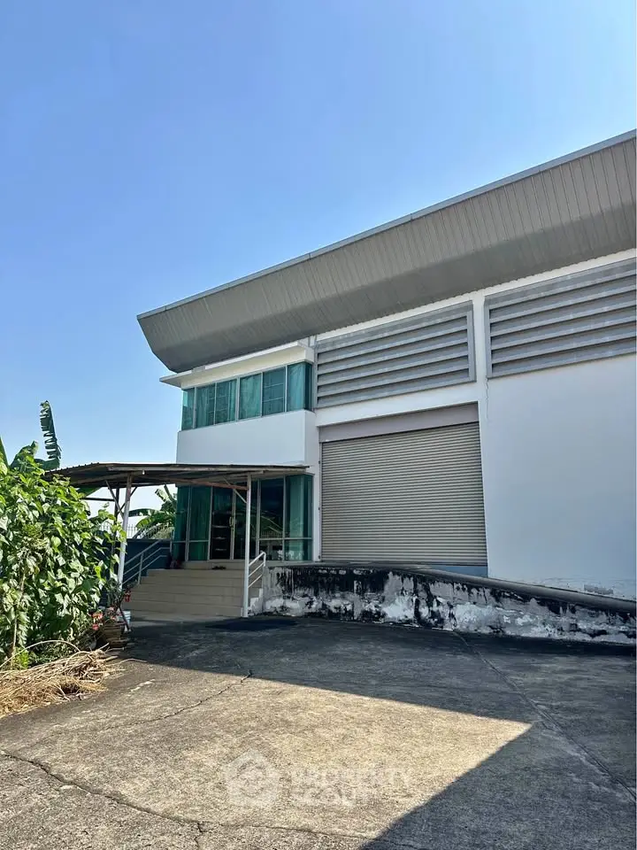 Modern industrial building with large roller door and sleek design, perfect for commercial use.