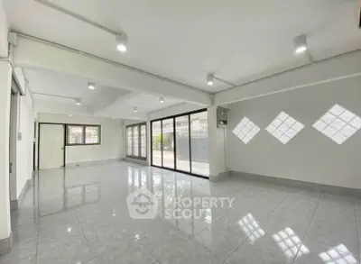 Spacious open-plan living room with large windows and modern lighting, perfect for natural light lovers.