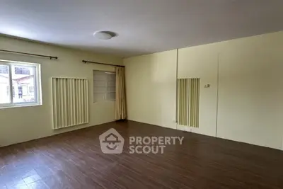 Spacious empty room with wooden flooring and large windows for natural light