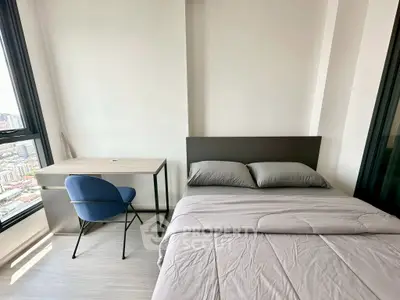 Modern bedroom with city view, featuring a cozy bed and stylish desk setup.