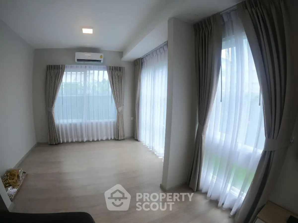 Spacious corner unit living room with large windows and elegant curtains