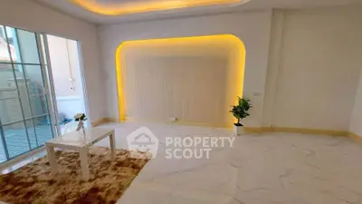 Modern living room with elegant lighting and marble flooring, featuring a cozy rug and minimalist decor.