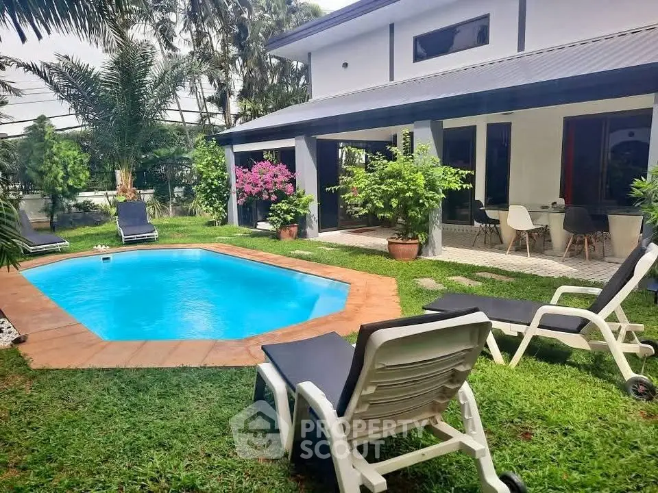 Charming backyard oasis with pool and lush garden in modern home exterior.